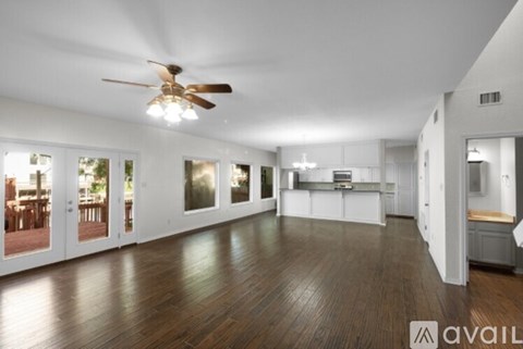 A spacious room with a ceiling fan and wooden flooring.
