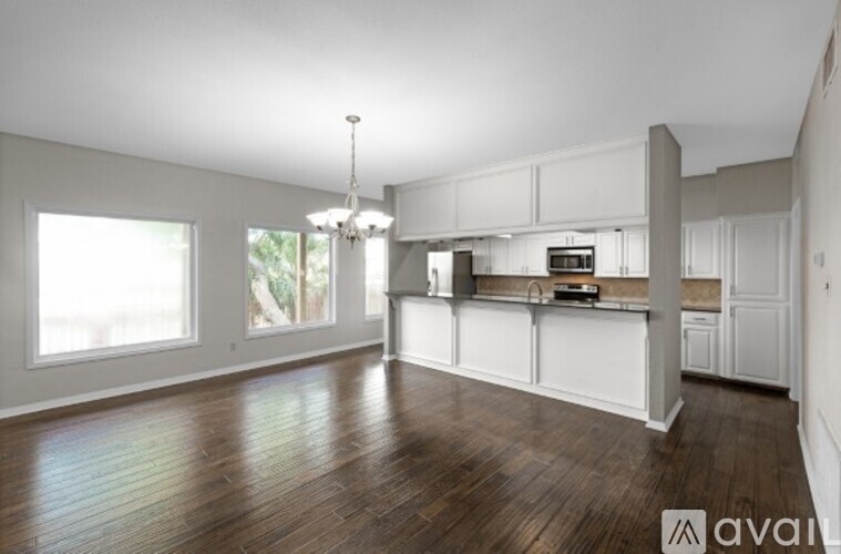 A spacious kitchen with white cabinets and a wooden floor.