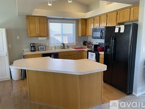 A kitchen with wooden cabinets and a black refrigerator.