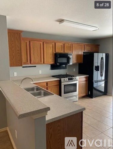 A kitchen with wooden cabinets and a black refrigerator.