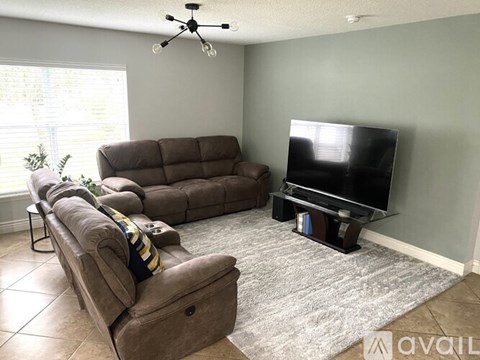 A living room with a brown sofa and a television on a stand.