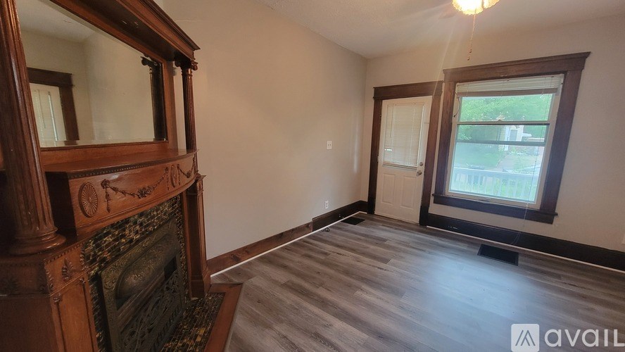 A room with a wooden fireplace and a mirror above it.