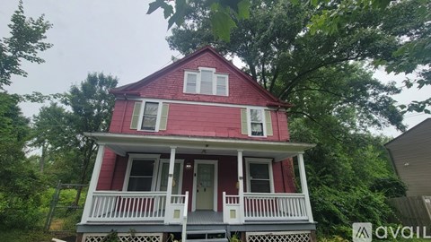 A red house with white railings and a porch.