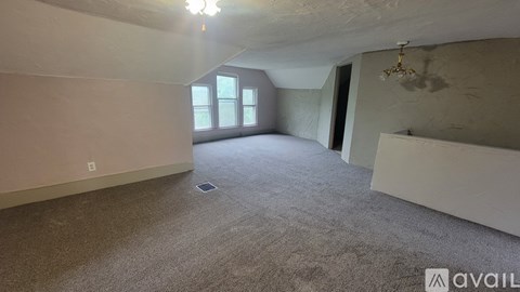 A spacious room with a carpeted floor and a window.