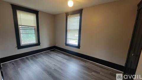 A room with a wooden floor and two windows.