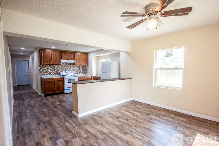 A kitchen with wooden floors and a ceiling fan.