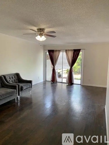 A living room with a grey couch and a ceiling fan.