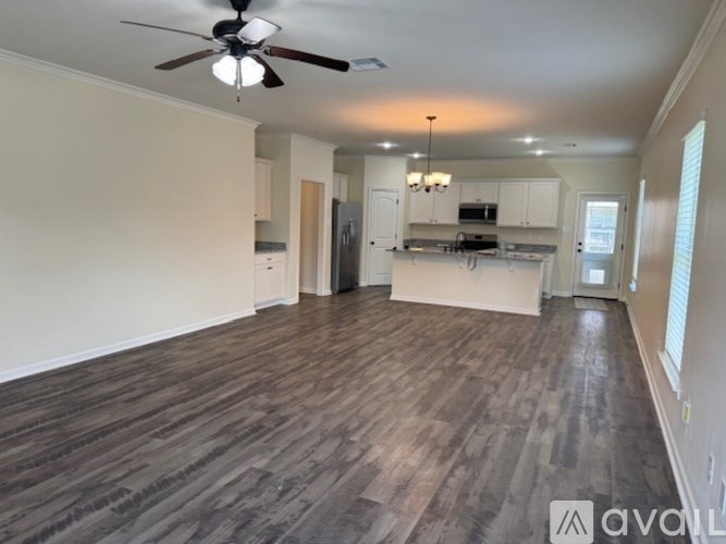 A spacious living room with wood flooring and a ceiling fan.