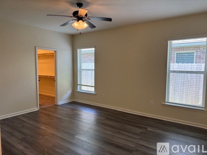 A room with a ceiling fan and two windows.