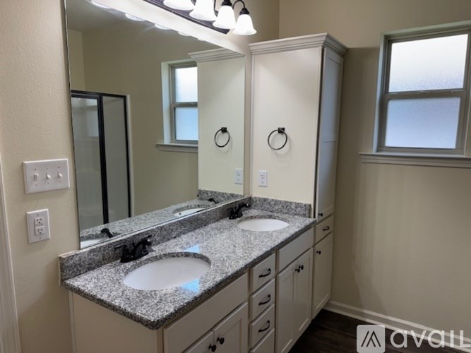A bathroom with a granite countertop and double sinks.