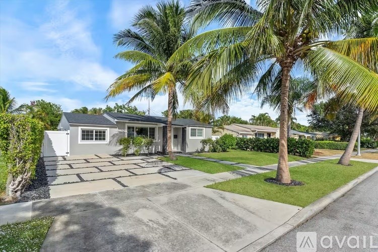 A house with a driveway and palm trees in front.