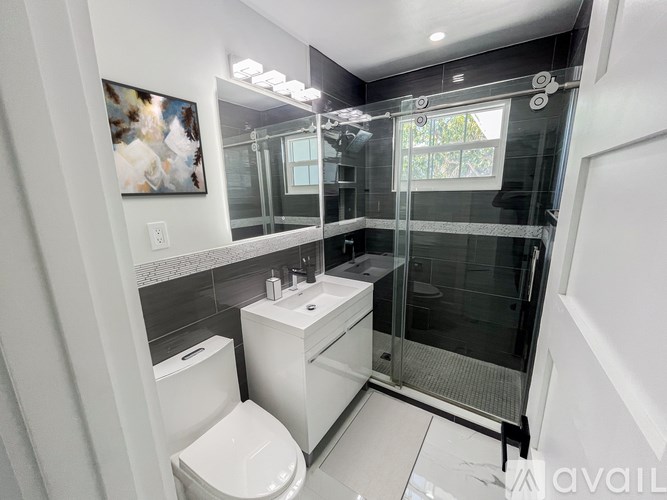 A modern bathroom with a toilet, sink, and shower.