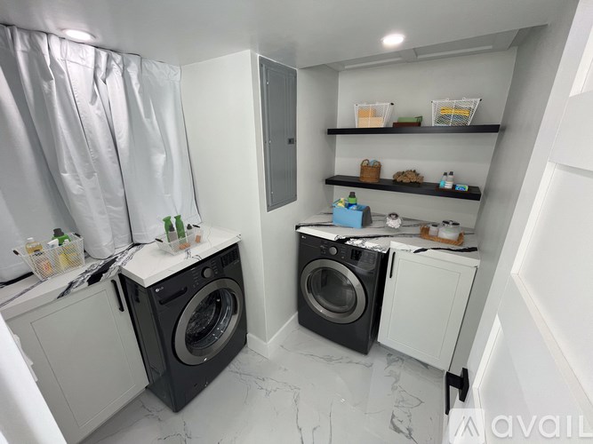 A laundry room with two washing machines and a shelf with various items.