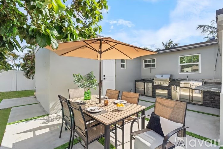 A patio with a table set for a meal under an umbrella.