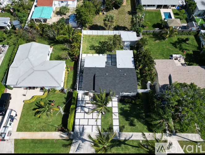 A house with a black roof is surrounded by greenery.