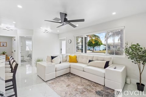 A modern living room with a white sofa set and a ceiling fan.