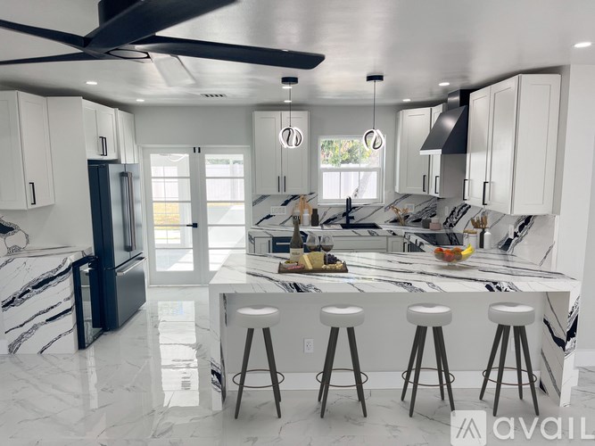 A modern kitchen with a marble countertop and bar stools.