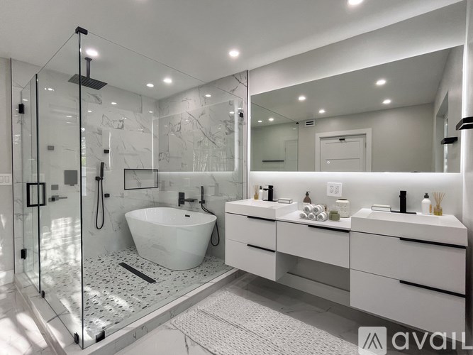 A modern bathroom with a white tub and double sinks.