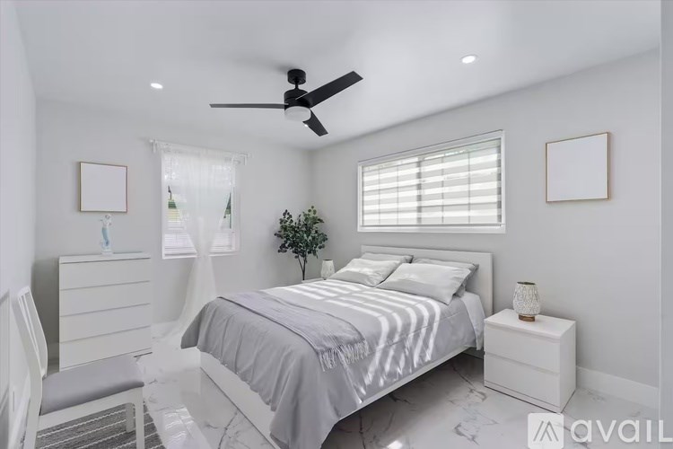 A bedroom with a bed, nightstand, and window with blinds.