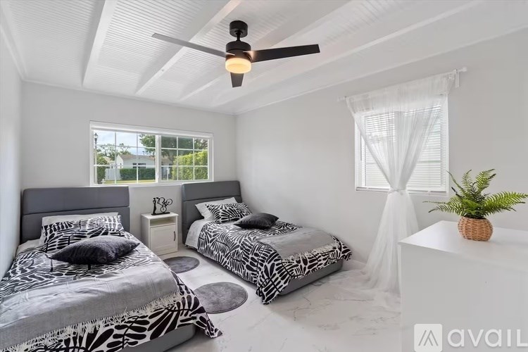 A bedroom with two beds and a ceiling fan.