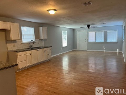 A kitchen with wooden floors and white cabinets.