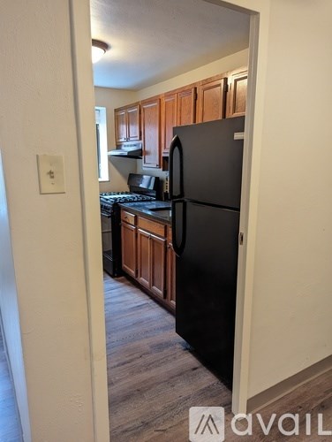 A kitchen with a black refrigerator and wooden cabinets.