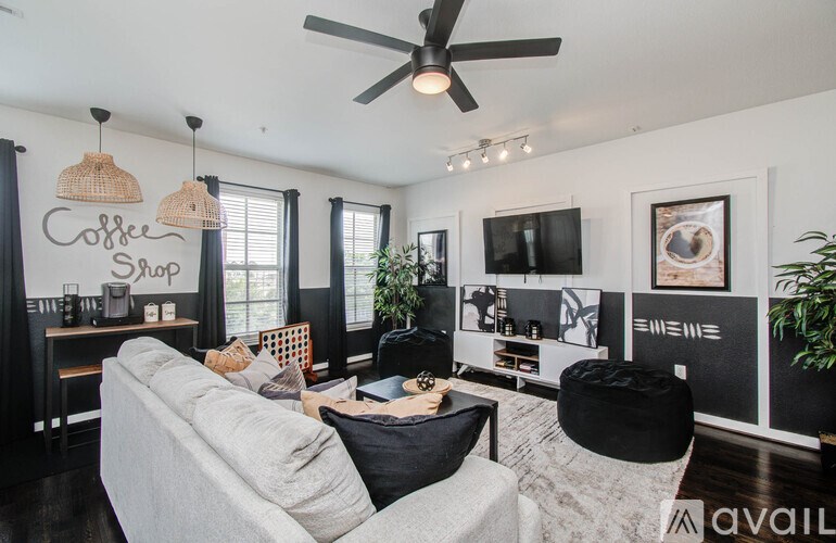 A living room with a grey couch and a coffee shop sign on the wall.