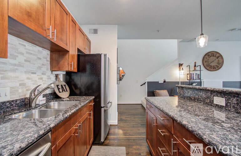 A kitchen with a black refrigerator and wooden cabinets.