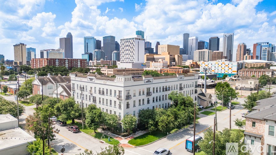 A cityscape with a large white building in the foreground and a skyline of tall buildings in the background.