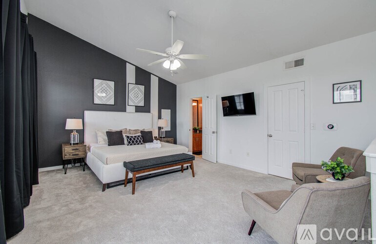 A bedroom with a bed, chair, and a ceiling fan.