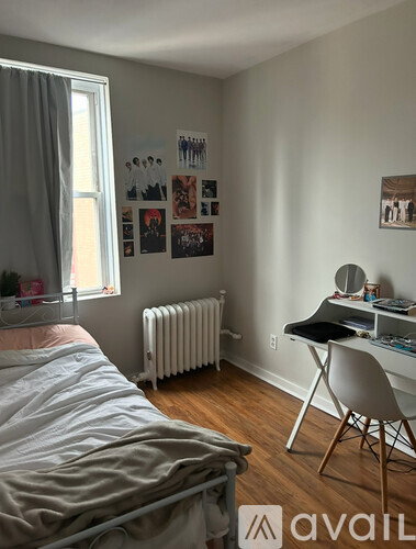 A bedroom with a bed, desk, chair, and pictures on the wall.