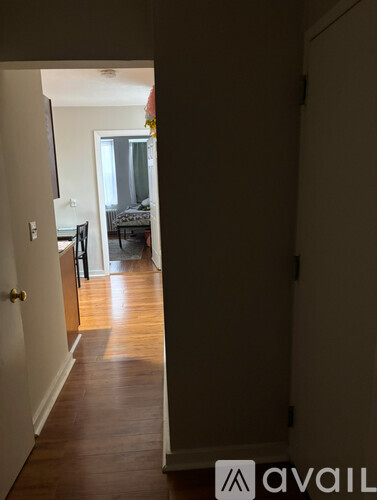A hallway with a door on the left and a living room in the distance.