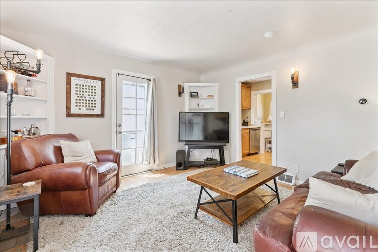 A living room with a brown leather couch, a wooden coffee table, and a television.