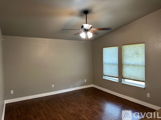 A room with a ceiling fan and two windows.