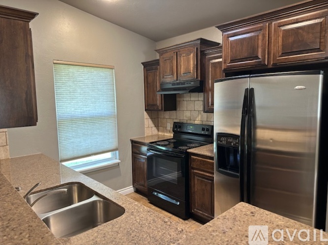 A kitchen with a stainless steel refrigerator, oven, and sink.
