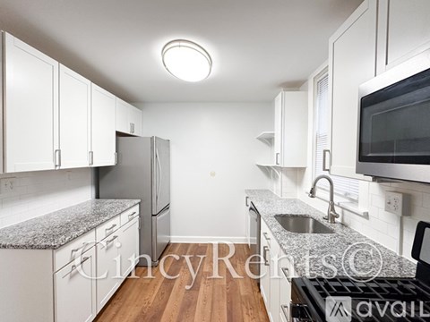 A kitchen with white cabinets and a granite countertop.