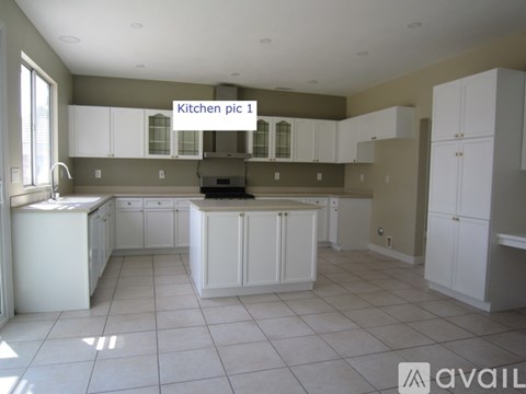 A kitchen with white cabinets and a tiled floor.