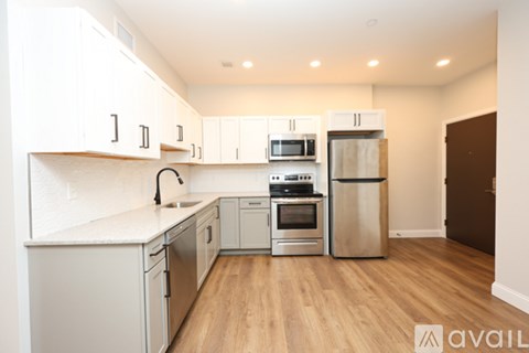 A kitchen with white cabinets and a wooden floor.
