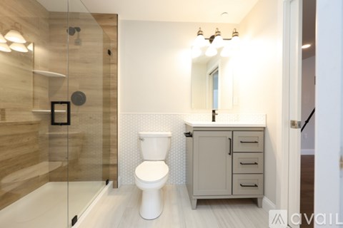 A white toilet sits in a modern bathroom with a glass shower.