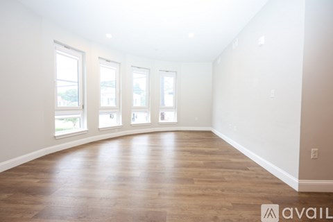 A room with wooden floors and four windows.