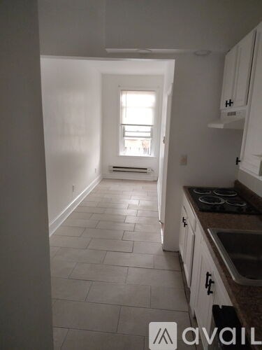 A kitchen with white cabinets and a tiled floor.