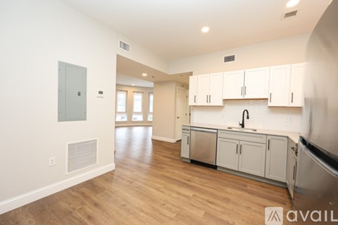 A kitchen with white cabinets and a wooden floor.
