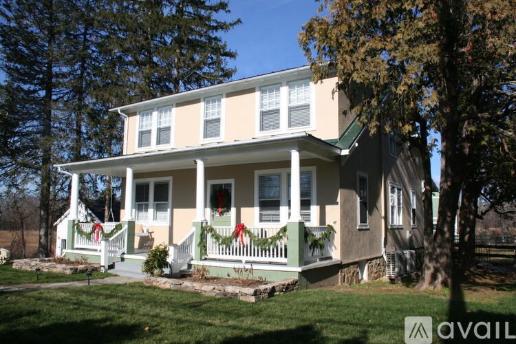 A two-story house with a green lawn and trees in the background.