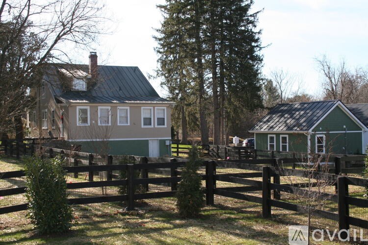 A house with a green roof is surrounded by a fence and trees.