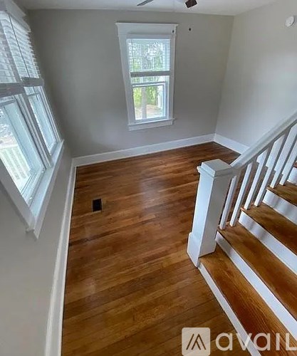 A room with wooden floors and a staircase leading to another room.