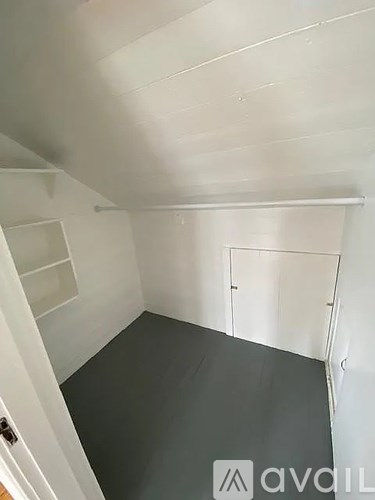 A white room with a grey floor and a white door.