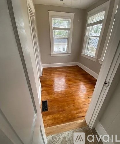 A room with wooden floors and two windows.