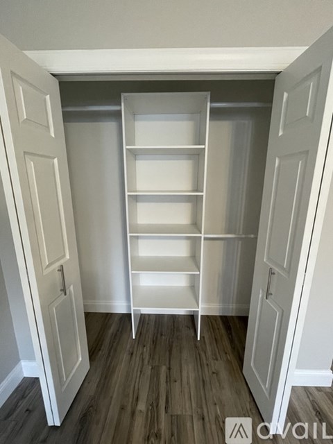 A white shelving unit in a room with wooden flooring.