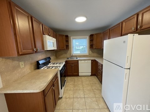 A kitchen with brown cabinets and a white refrigerator.