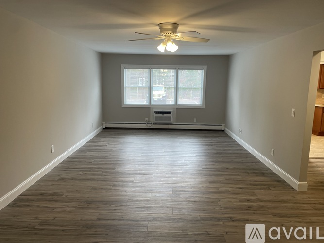 A spacious room with wooden flooring and a ceiling fan.